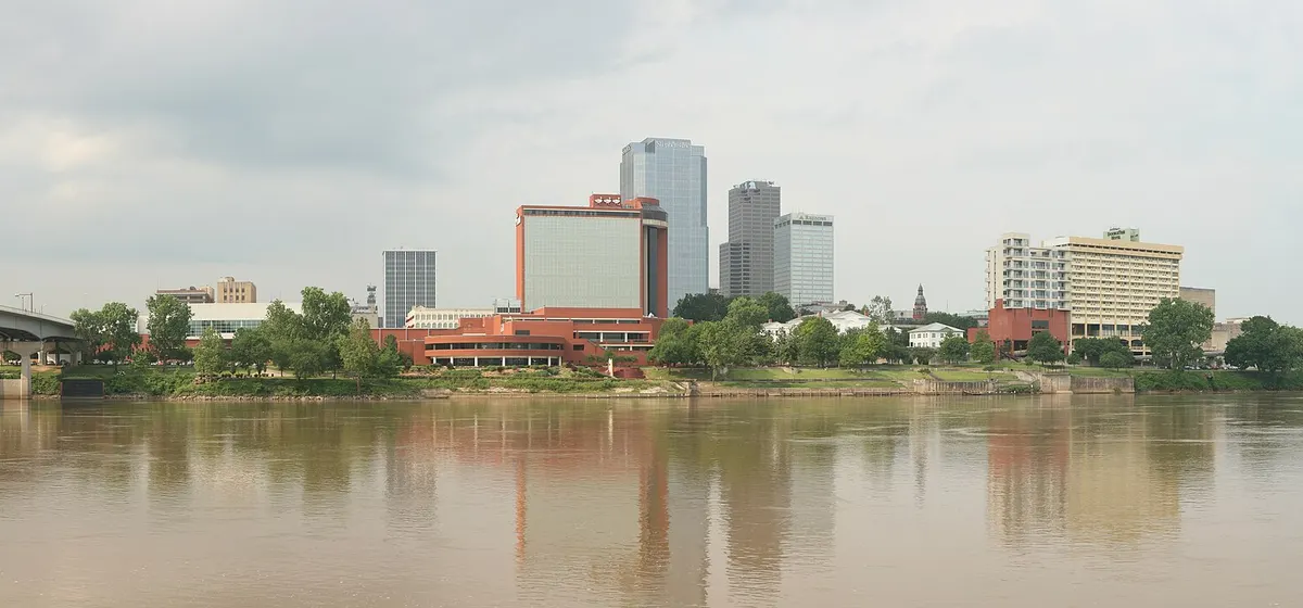 Downtown Little Rock's towers along the far bank of the wide Arkansas River under a grey sky