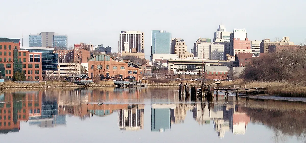 Downtown Wilmington's office towers reflected in still water along the riverfront