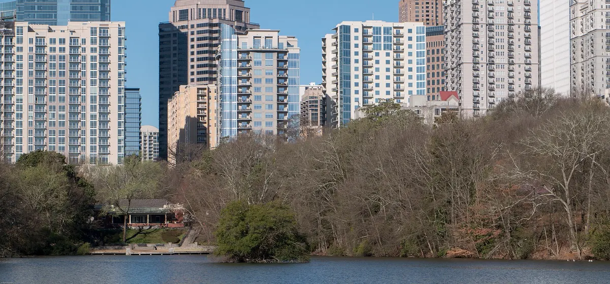 Midtown Atlanta's apartment and office towers rising above the trees beyond Lake Clara Meer in Piedmont Park