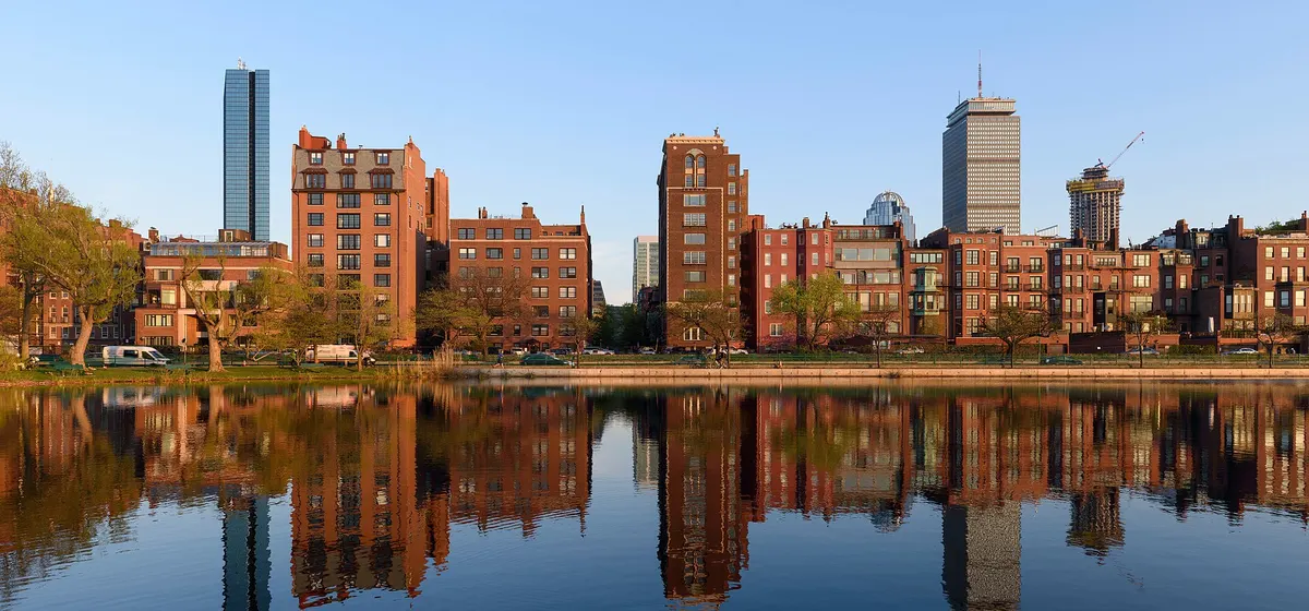 Back Bay's brick rowhouses and towers reflected in still water along the Charles River Esplanade