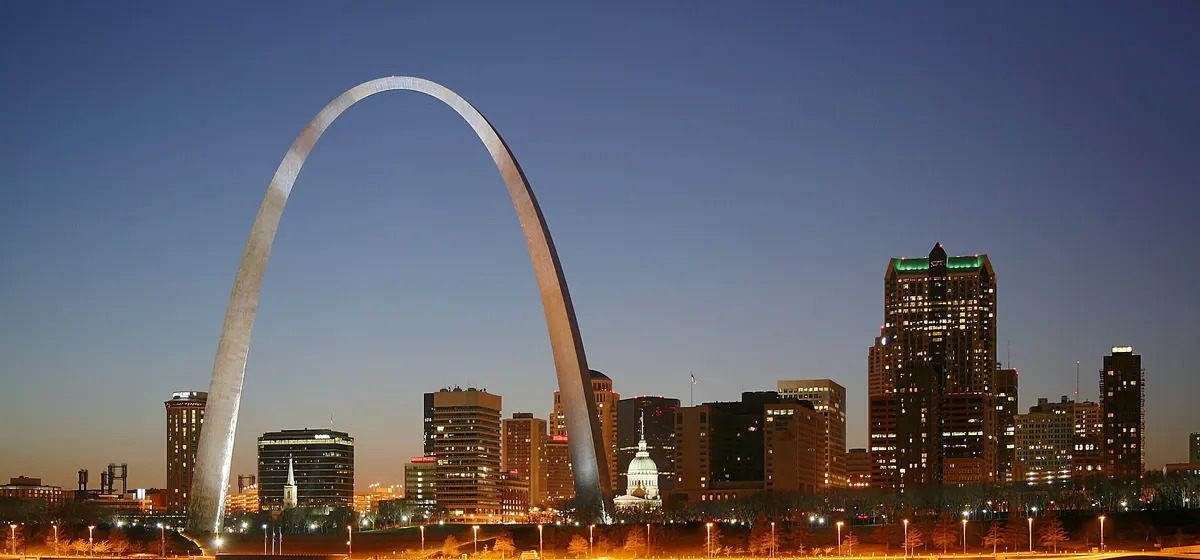 The Gateway Arch and downtown St. Louis lit at night, reflected in the Mississippi River