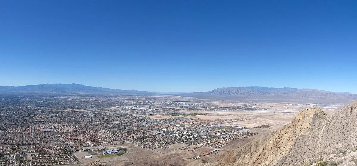 The Las Vegas Valley spread across the desert floor beneath a clear blue sky, with mountains on the far side