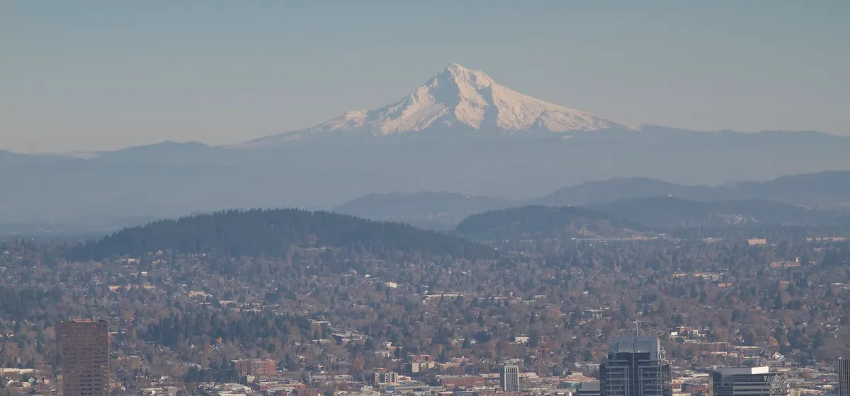 Downtown Portland's towers in front of the city's neighborhoods, with the snow-capped cone of Mount Hood on the horizon