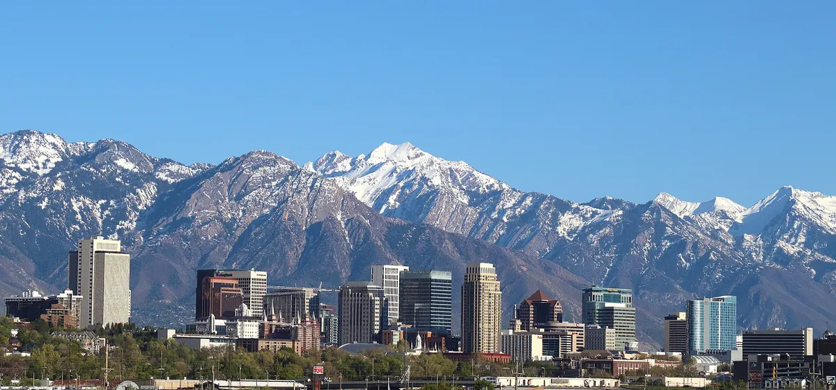 Downtown Salt Lake City's towers in front of the snow-capped Wasatch Range under a clear blue sky